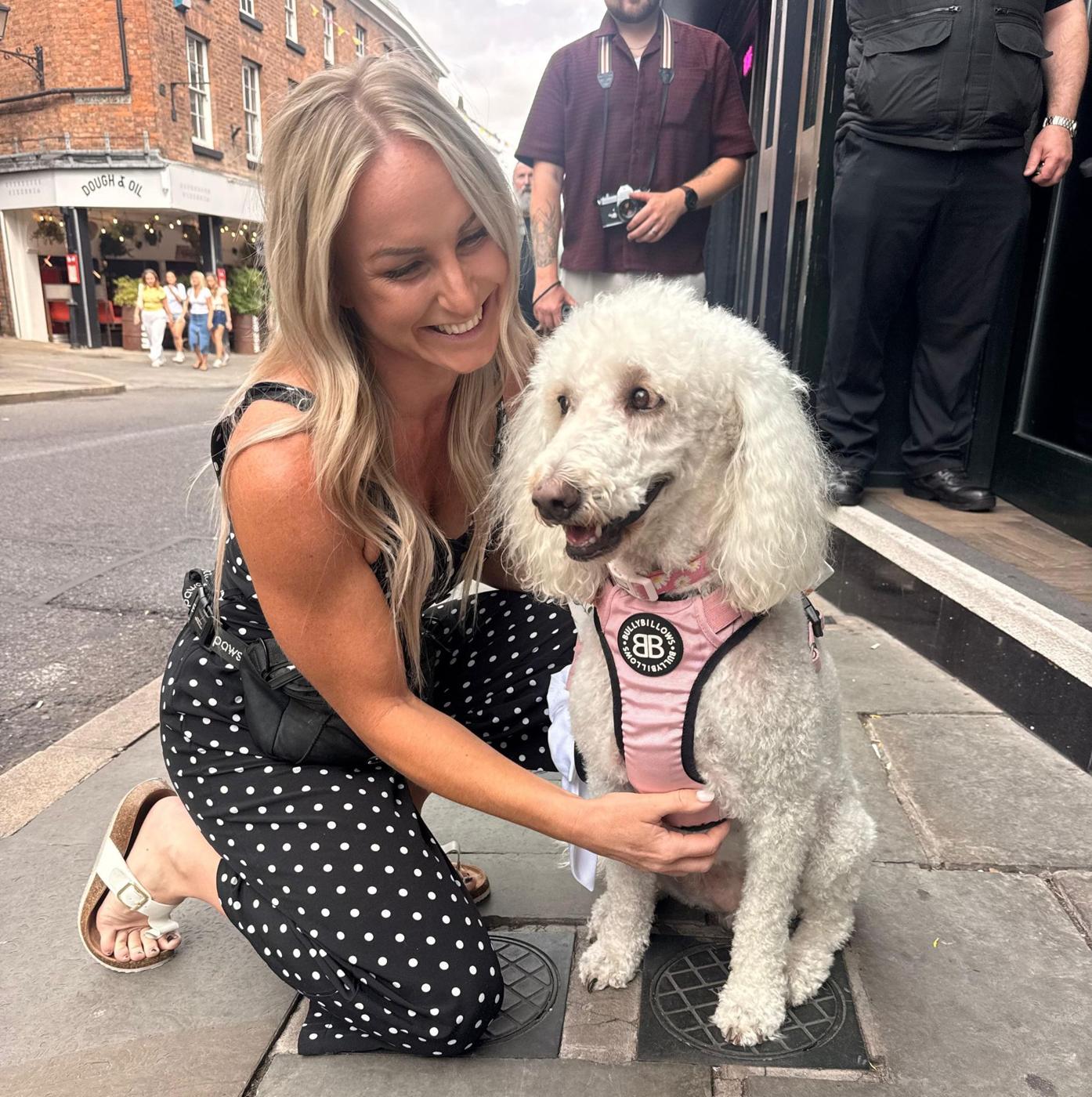 Cheryl smiling with a white poodle in town